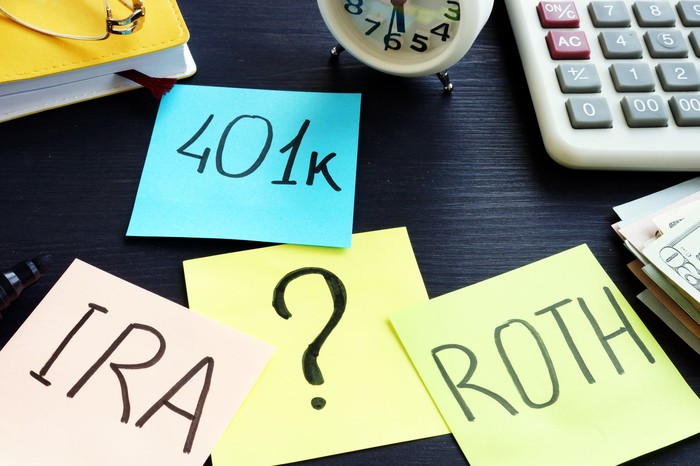Desktop with sticky notes labeled as 401k, Roth, and IRA. 